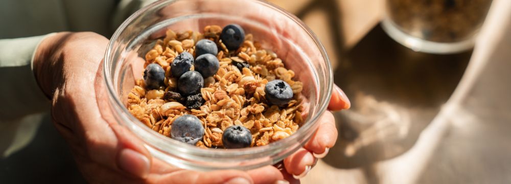 Woman holding bowl of oats and blueberries